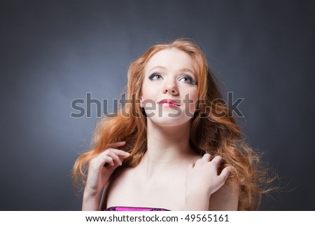 Beauty portrait of a sensitive red-haired woman holding hands near shoulders