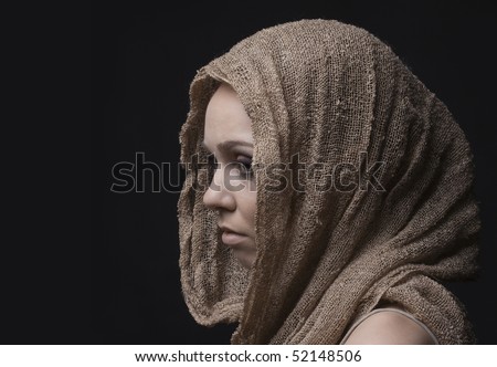 Studio closeup portrait of beautiful sad woman with skarf on head