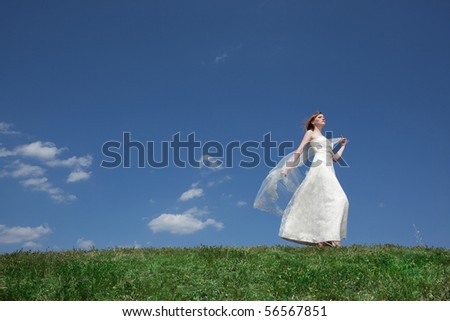 Dreamy beautiful blonde bride walking alone in the park enjoying wind wave