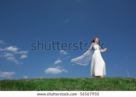Dreamy beautiful blonde bride walking alone in the park enjoying wind wave