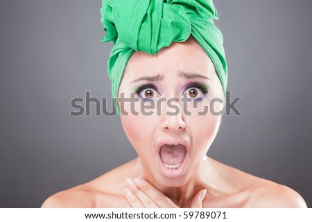 Skared woman with green scarf on head with wow expression; open mouth