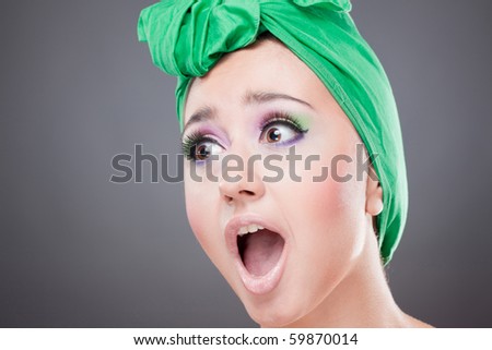 Skared woman with green scarf on head with wow expression; open mouth