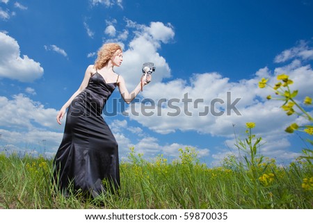 Beautiful pashionate woman standing on field filming with old camera