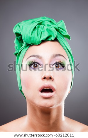 Amased woman with green scarf on head with wow expression; open eyes and mouth