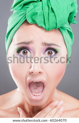 Scared woman with green scarf on head with wow expression; open mouth