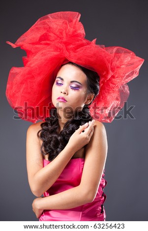 Dreaming beautiful brunette woman in red tulle hat embracing herself