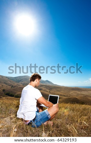 Young man working on laptop in the mountains