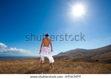 Glamour young man standing back in white skirt in mountains