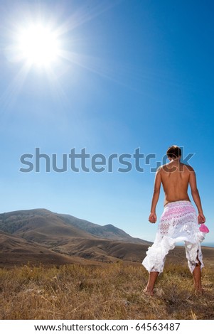 Glamour young man standing back in white skirt in mountains