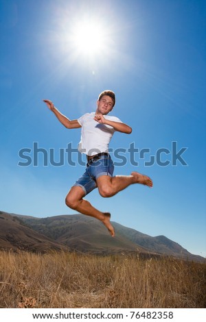 Happy young man jump in the mountains looking at camera