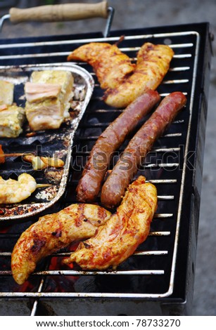 Meat, fish, bread and sausage beeing broiled on the barbecue grill.