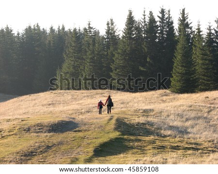 Family hike. Mother and daughter walking on the autumnal grassland.