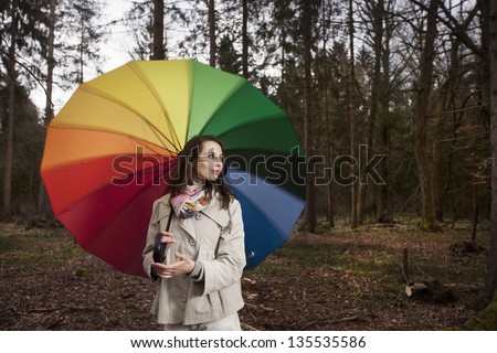 Young woman in the forest, with brightly colored umbrella
