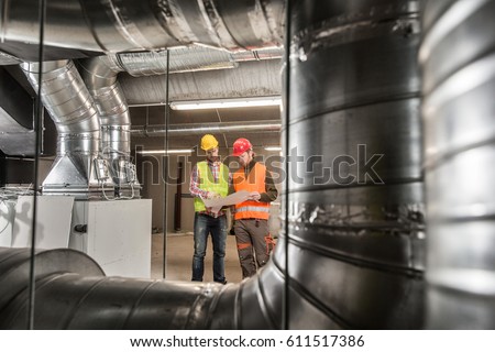 Workers making final touches to HVAC system. HVAC system stands for heating, ventilation and air conditioning technology. Team work, HVAC, indoor environmental comfort concept photo.