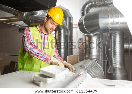 Worker making final touches to HVAC system. HVAC system stands for heating, ventilation and air conditioning technology. Team work, HVAC, indoor environmental comfort concept photo.