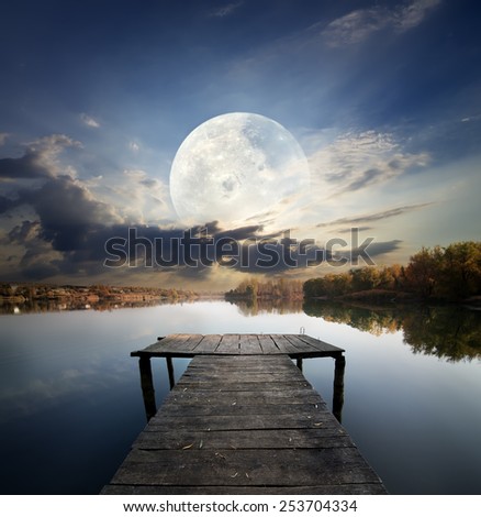 Fishing pier on a river under fool moon. Elements of this image furnished by NASA