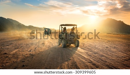 Buggies in sand desert at the sunset