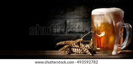 Beer in mug on wooden table near brick wall