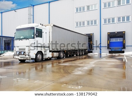 Unloading big container trucks at warehouse building
