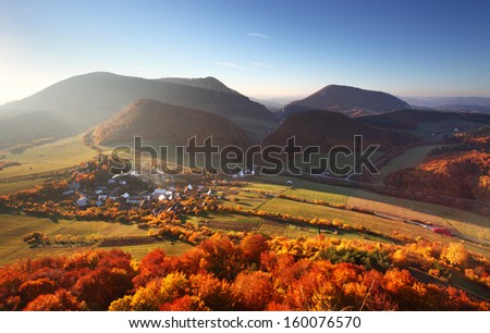 Aerial view on small town - colorful fields and trees in autumn,
