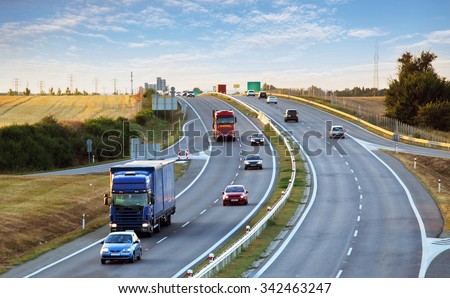 Highway traffic in sunset with cars and trucks