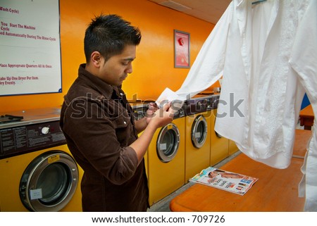 A man inspecting a stain on his clothes at a local laundromat.