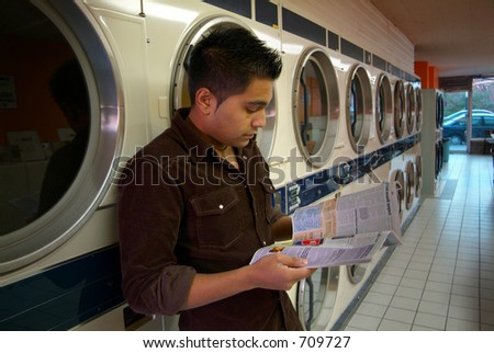 A man waiting for his clothes to dry at a local laundromat.