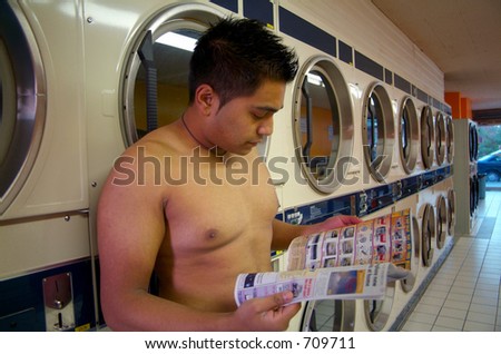 A naked man waiting for his clothes to dry at a local laundromat.