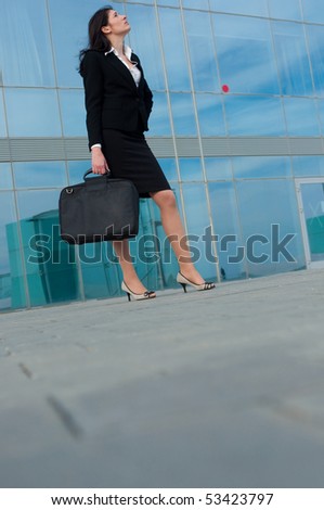 Business woman posing with a laptop\'s bag in a front of modern office building