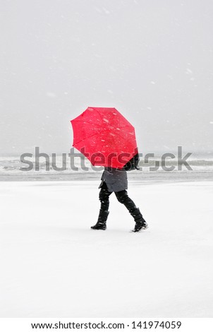 person with red umbrella in snow storm