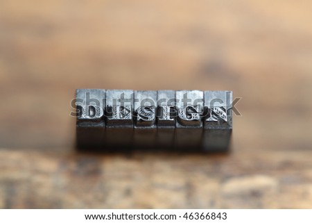 the word design in letterpress type on a wooden background.
