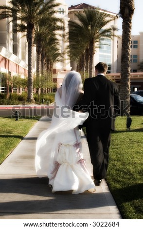 Wedding couple walking with bride\'s veil flowing in the breeze.  Soft glow effect to accentuate the movement of the bride\'s veil