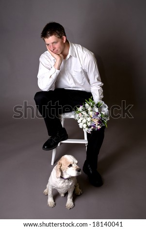 Young groom in thoughtful pose with a dog at his feet.  They could be sharing the same bed soon.