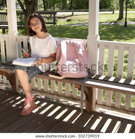Grade school girl doing homeowrk outside on school grounds on a sunny day