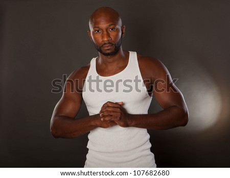 Young, handsome, muscular black man in a t-shirt with hands together