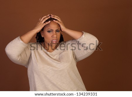 Frustrated beautiful plus size black woman standing on a brown background