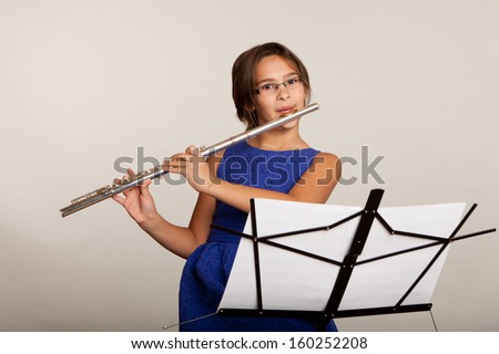 Young girl in a blue dress playing a flute
