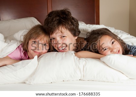 Shots of a mother and her two daughters waking up in bed with white linens part of a series