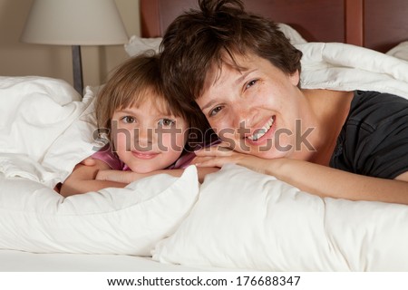Shots of a mother  daughters waking up in bed with white linens part of a series