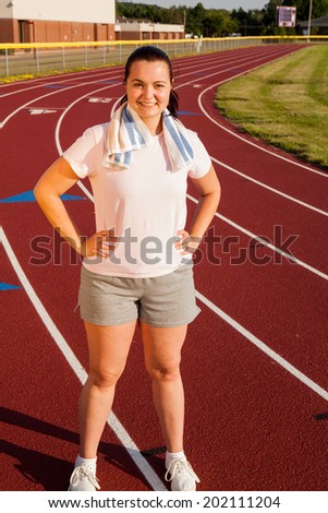 Young Caucasian woman exercising outside on a track at a high school sports complex late in the afternoon