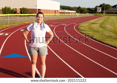 Young Caucasian woman exercising outside on a track at a high school sports complex late in the afternoon
