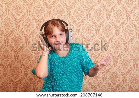 Gradeschool girl at home listening to music on a pair of vintage 1970s wired headphones