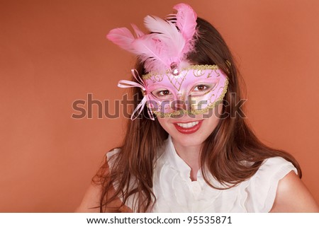 Mardi Gras - Beautiful young adult woman wearing a carnival mask against an earth tone background