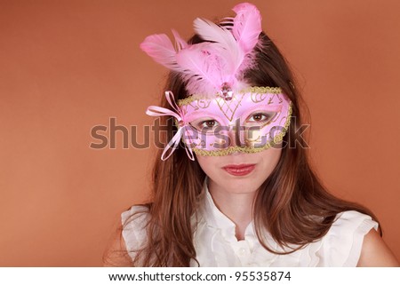 Mardi Gras - Beautiful young adult woman wearing a carnival mask against an earth tone background
