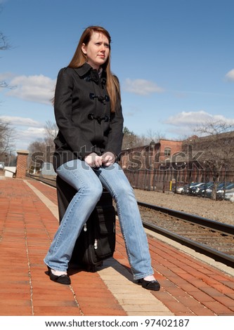 Beautiful redhead sitting on her luggage waiting for the train