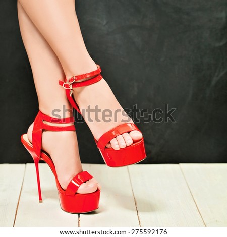 Woman Legs wearing High Heels Red Shoes on Dark. Fashion Background