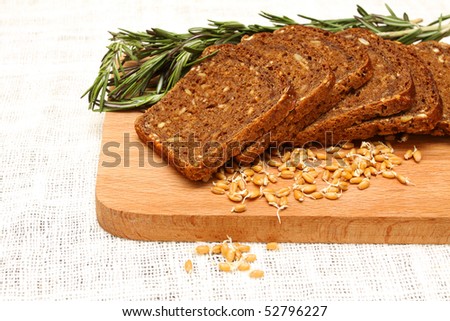 Bread, rosemary and wheat germ on a wooden board on the white linen tablecloths