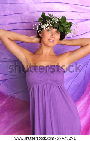 Beautiful sensual woman in summer dress and wreath of flowers and leaves on a purple and lilac background. Series