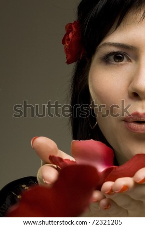 Beautiful passionate woman kisses red rose petals