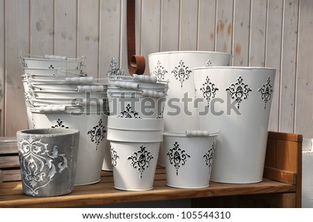 White buckets and garden pots on an old wooden shelf in soft sunlight from the side.